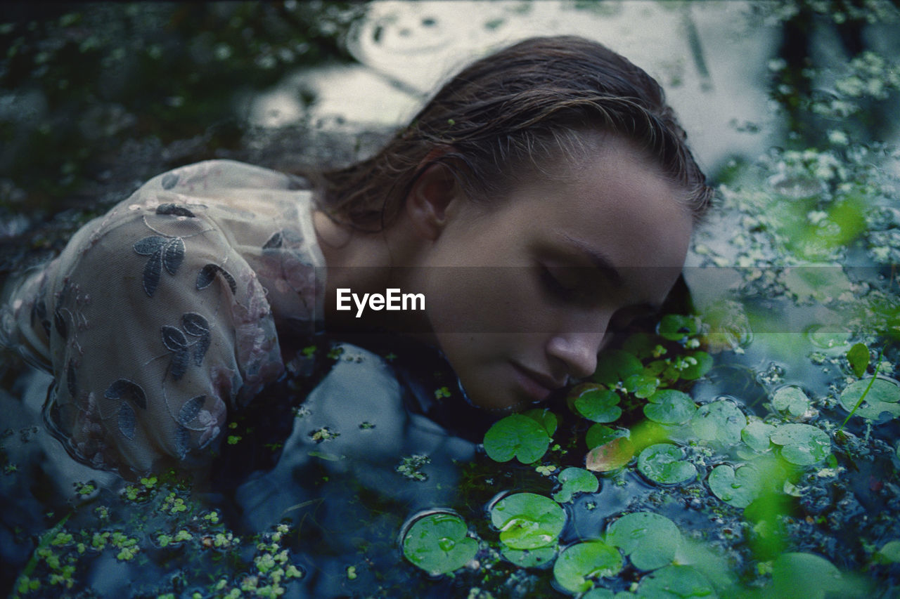 A woman in a white dress on the surface of a swamp water in the forest