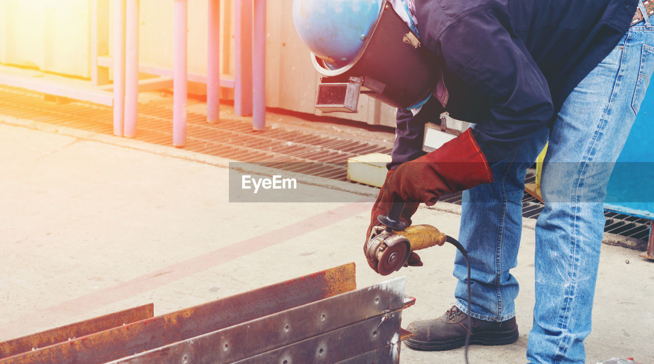 Construction worker grinding metal at site