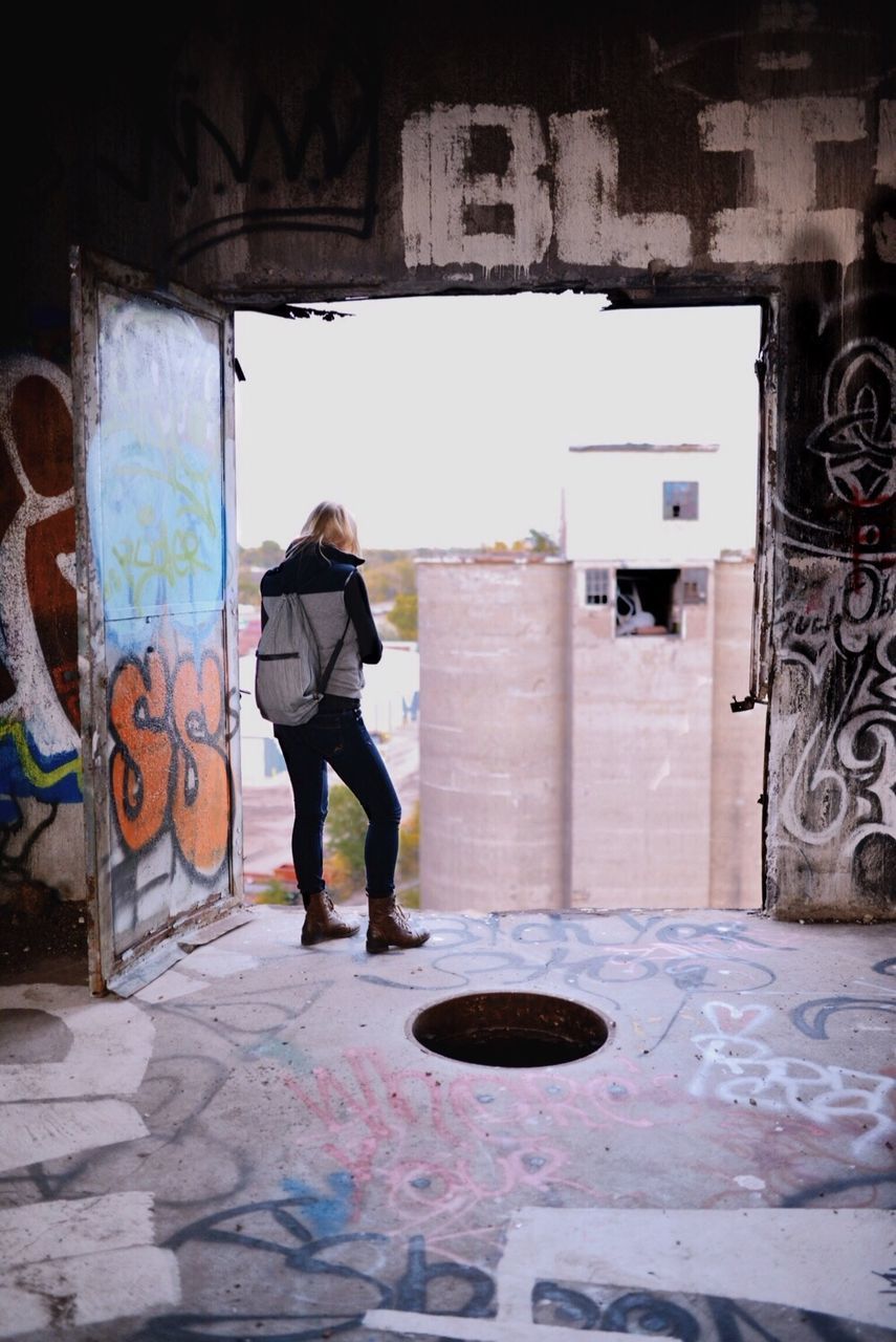 Woman standing on edge of upper storey of abandoned building