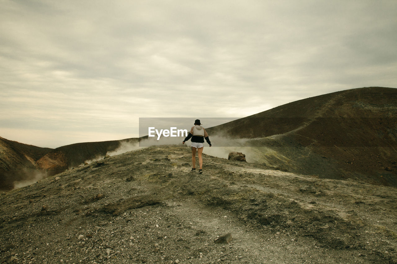 Rear view of woman walking on rocky landscape