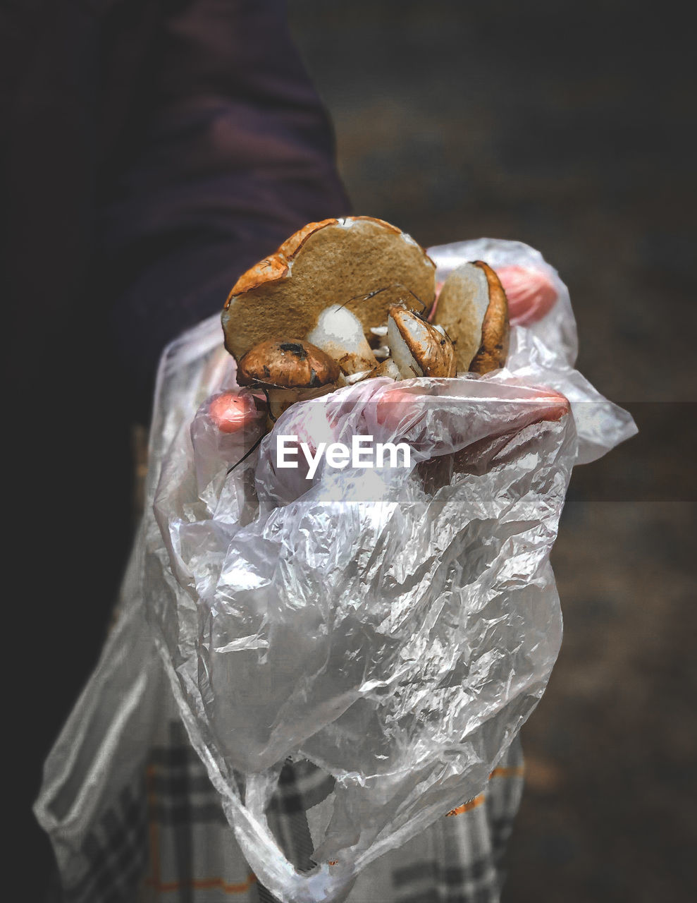 CLOSE-UP OF HAND HOLDING ICE CREAM CONE IN PLASTIC