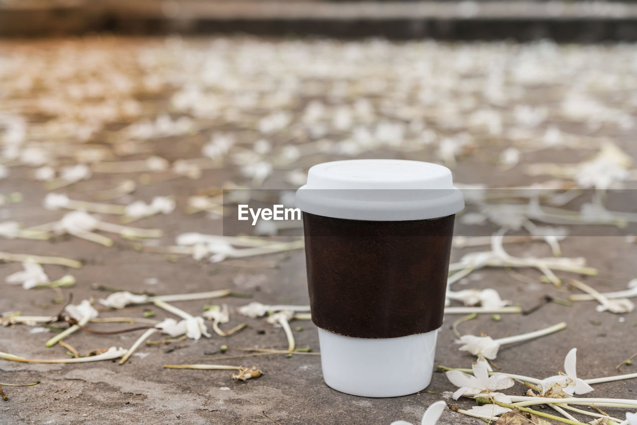 White glass coffee cup in the morning nature flower background in park