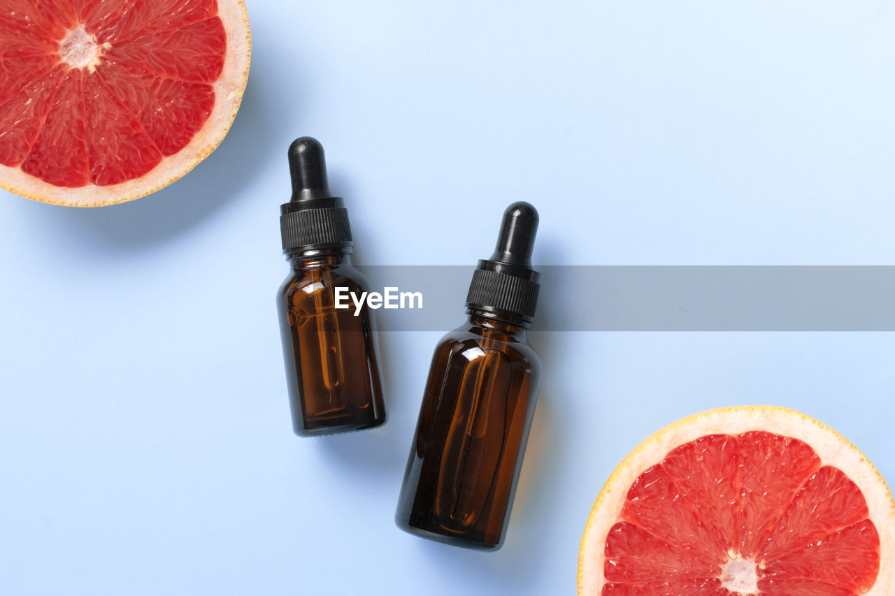 Bottle of grapefruit essential oil on light blue background