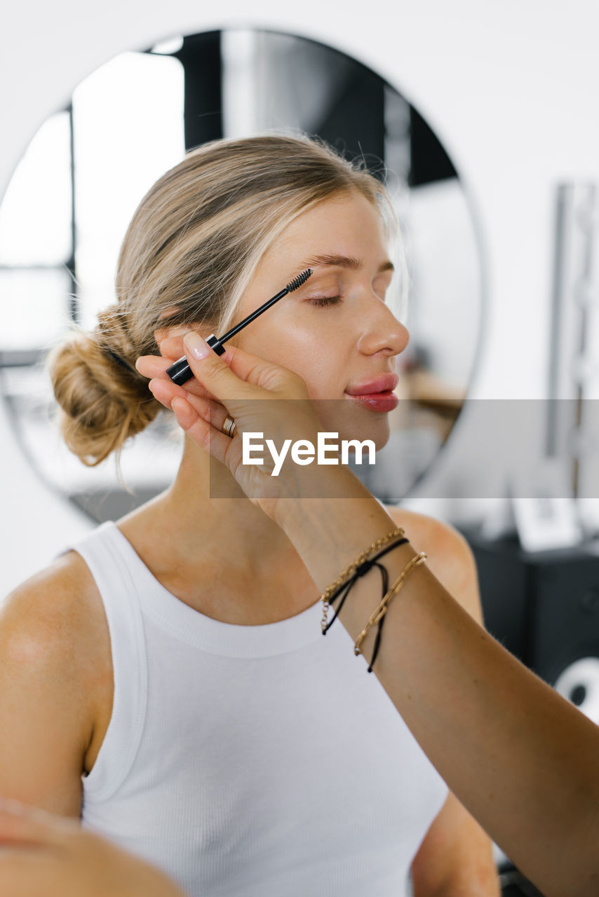Make-up artist makes a woman's makeup, apply mascara with a brush to her eyelashes
