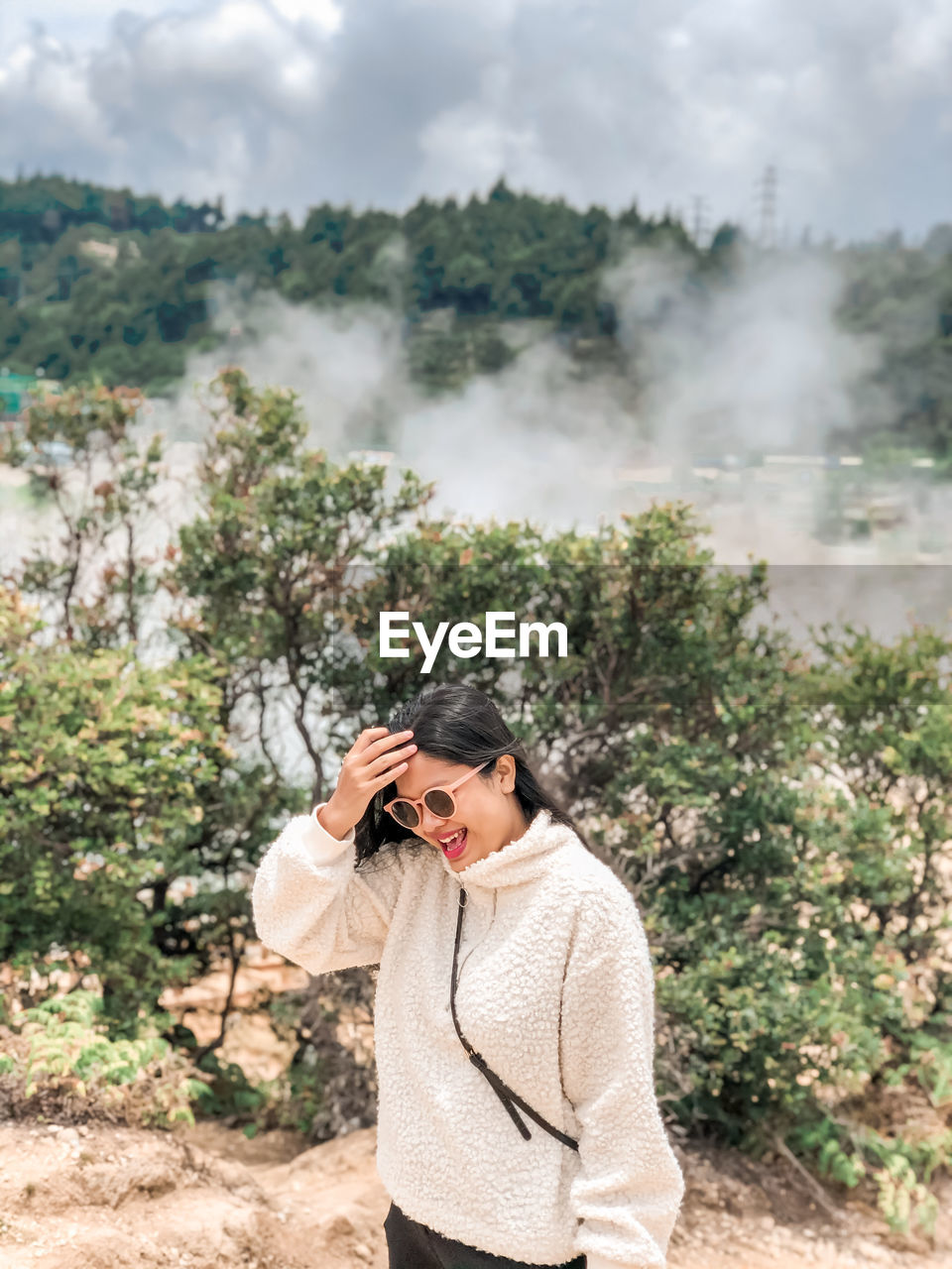 Young woman using phone while standing on land