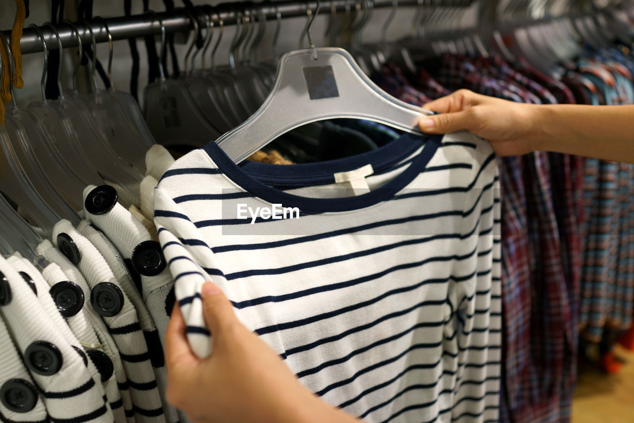 Cropped hands of woman buying t-shirt at store