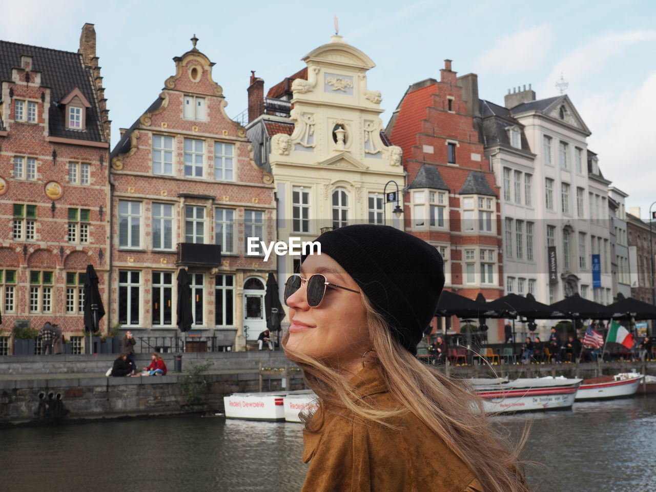 PORTRAIT OF WOMAN AGAINST BUILDINGS IN CANAL