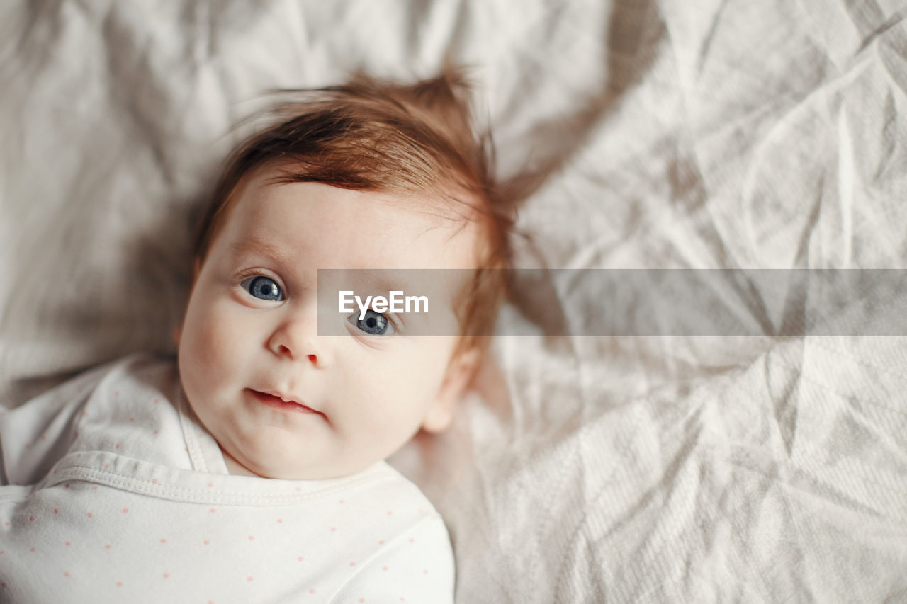 Portrait of cute baby lying on bed at home