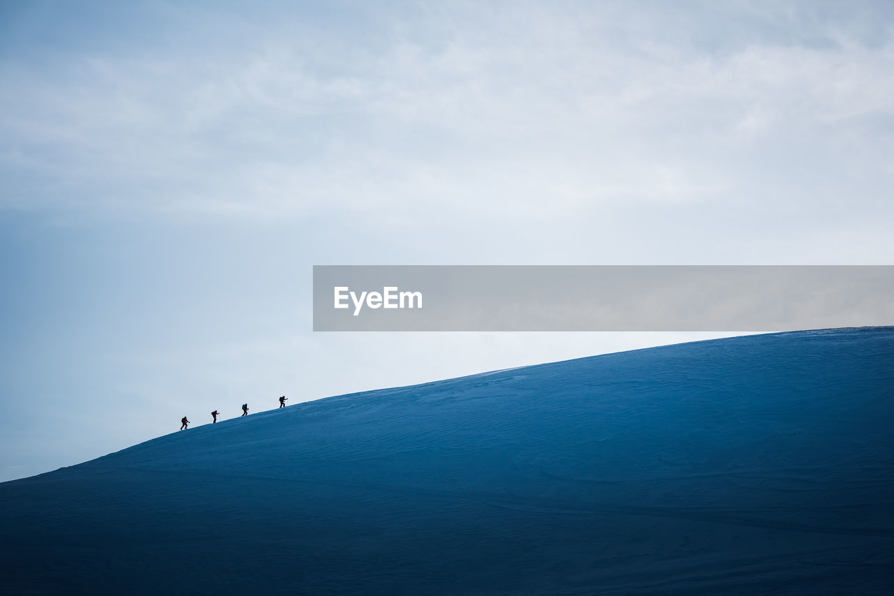 A group of skiers walks across a snowy ridge in iceland