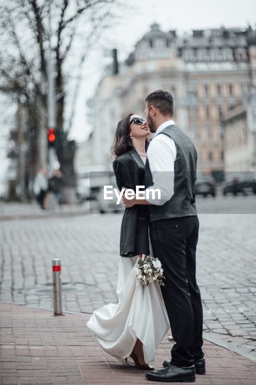 Full length of bridegroom embracing on street