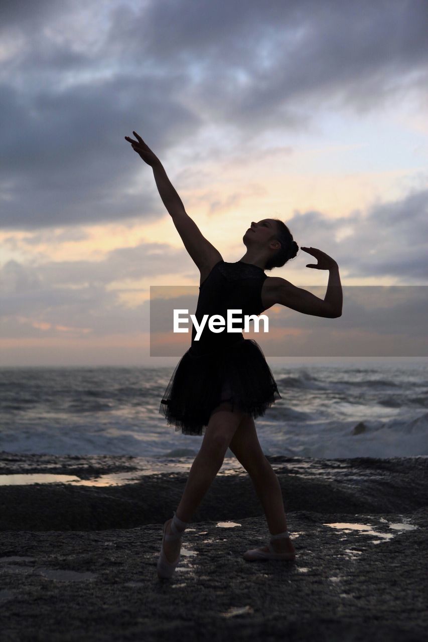 Silhouette young woman performing ballet at beach