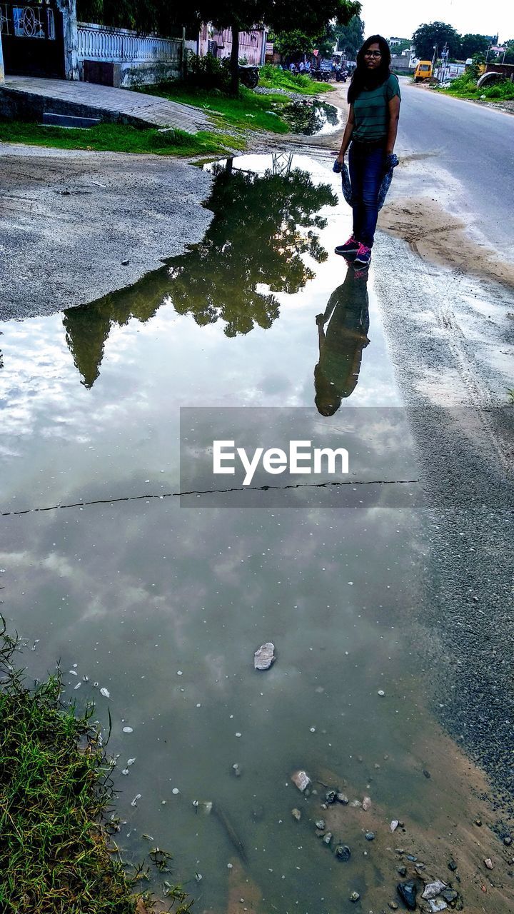 REFLECTION OF WOMAN ON PUDDLE AT LAKE