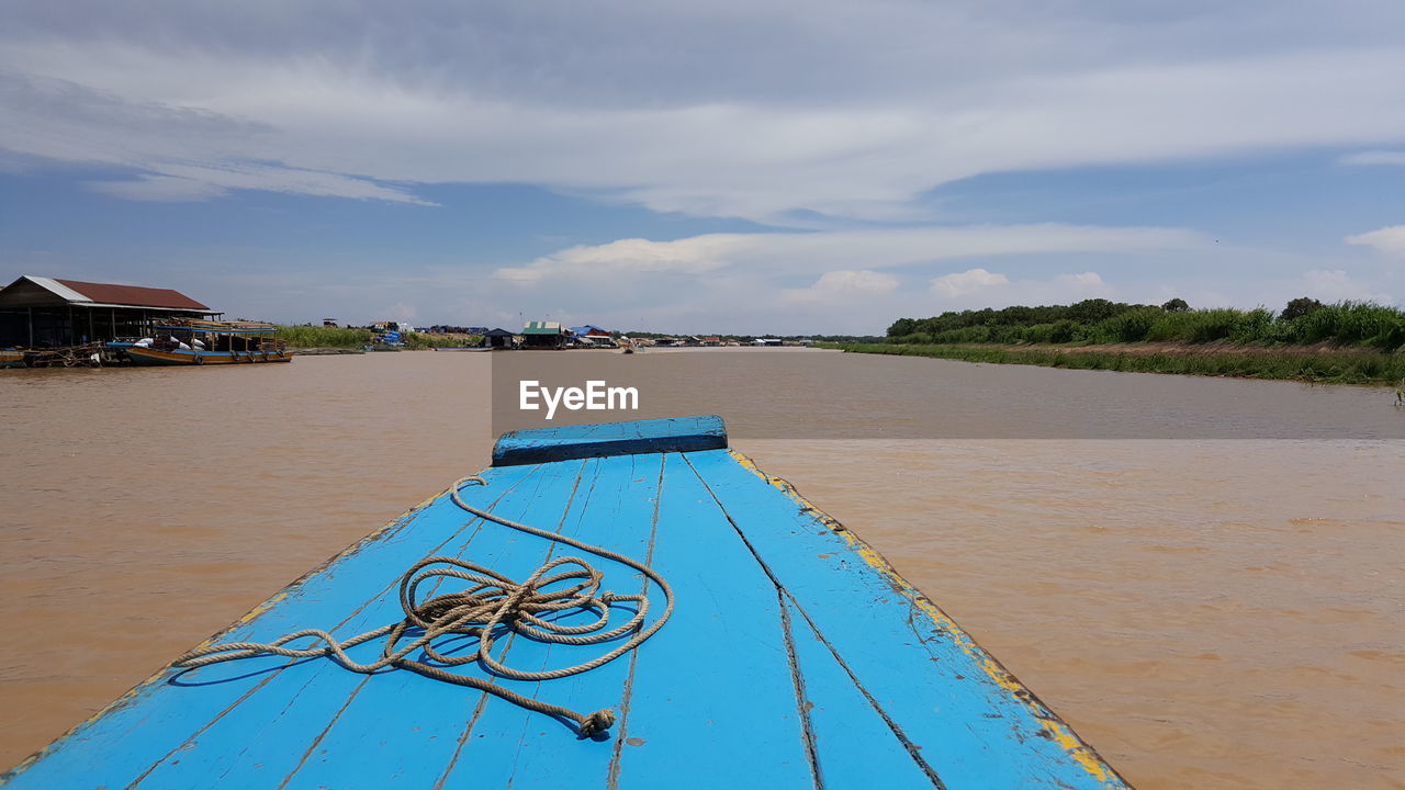 Rope on blue boat sailing in river against sky