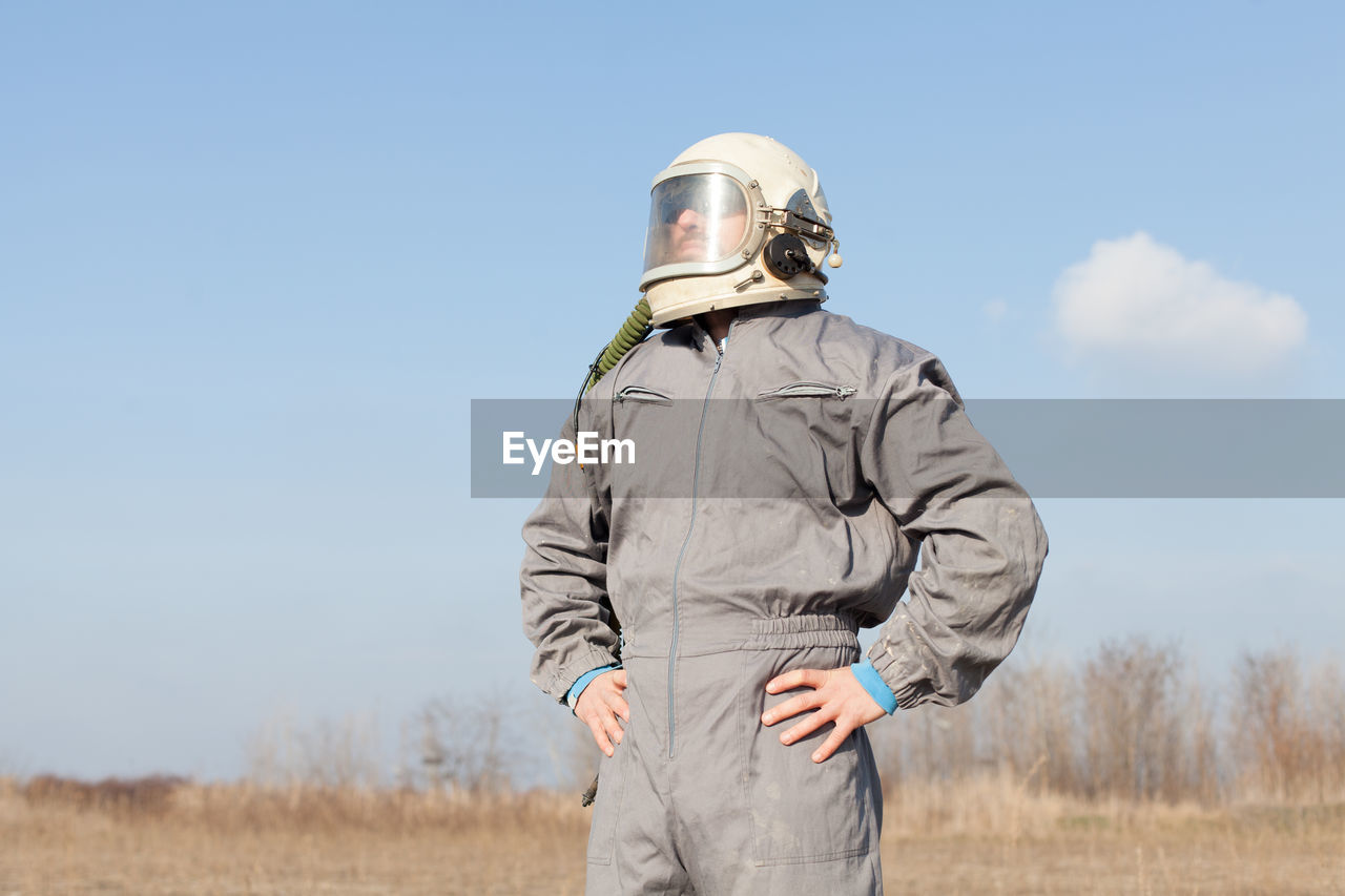 Mid adult man wearing protective workwear standing on field against sky