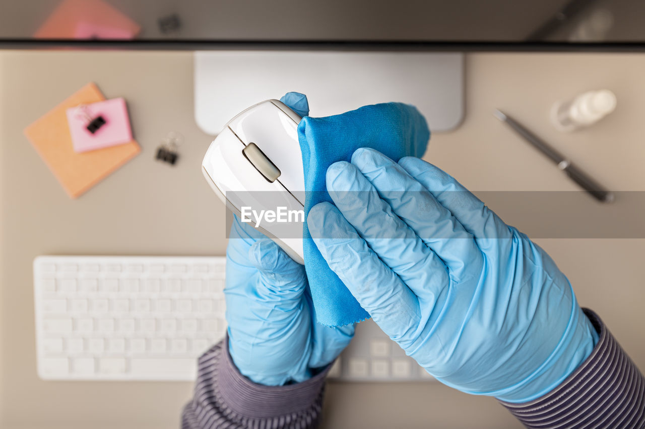 Cropped hands wearing gloves cleaning mouse