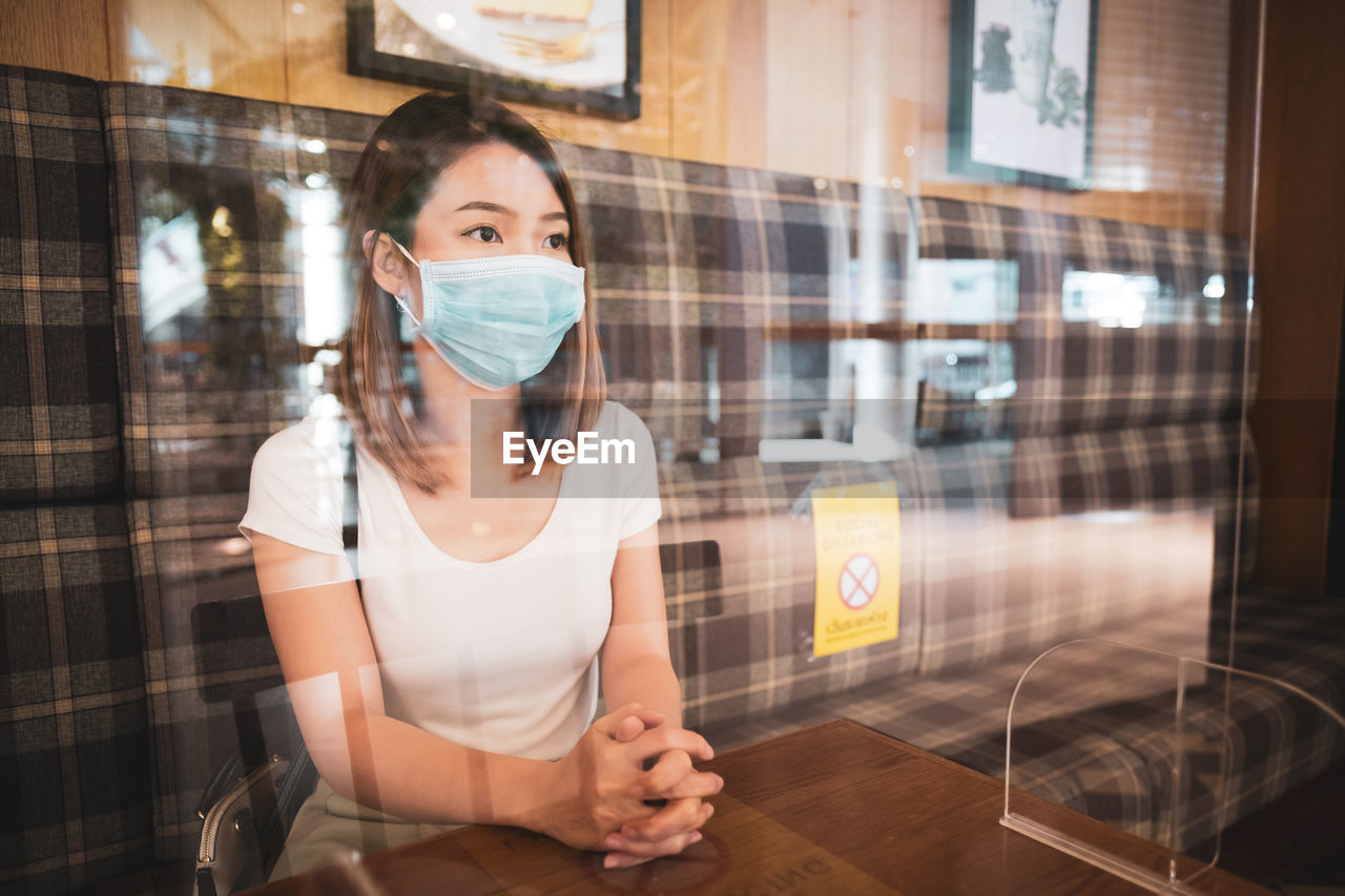 Woman wearing mask while sitting at cafe