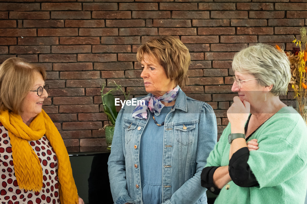 portrait of couple standing against brick wall