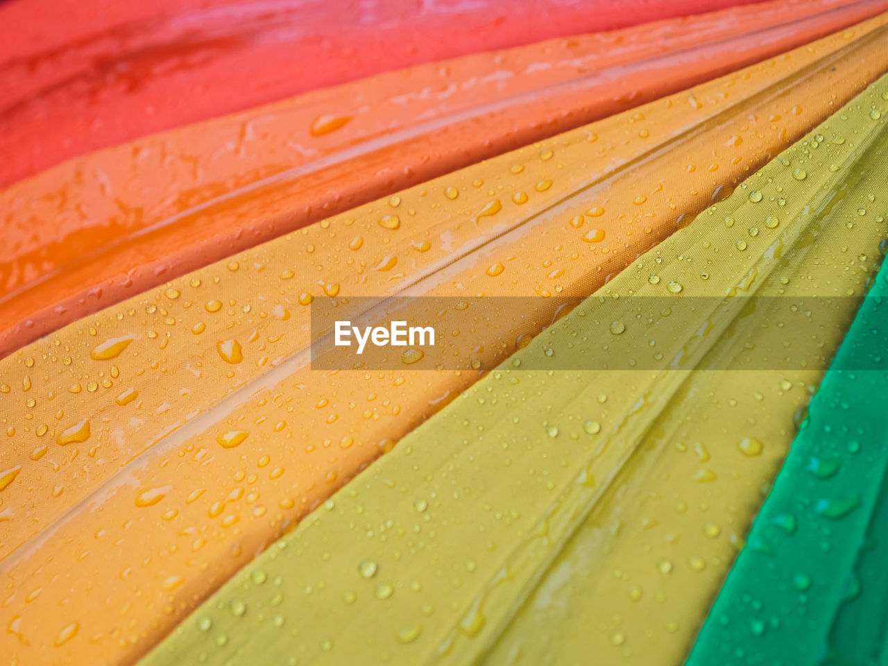 Close-up of colorful umbrellas and raindrops, top view