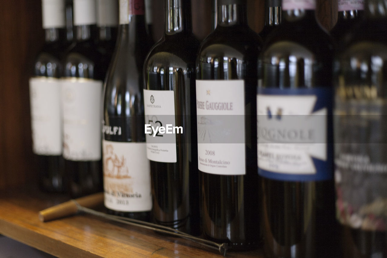 CLOSE-UP OF WINE BOTTLES IN SHELF