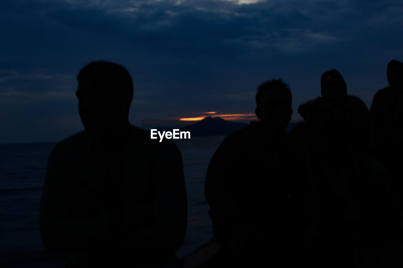 Rear view of silhouette people against sea at sunset