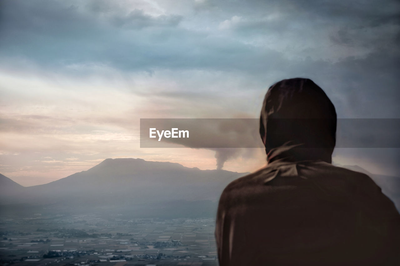 Rear view of man looking at mountain against sky