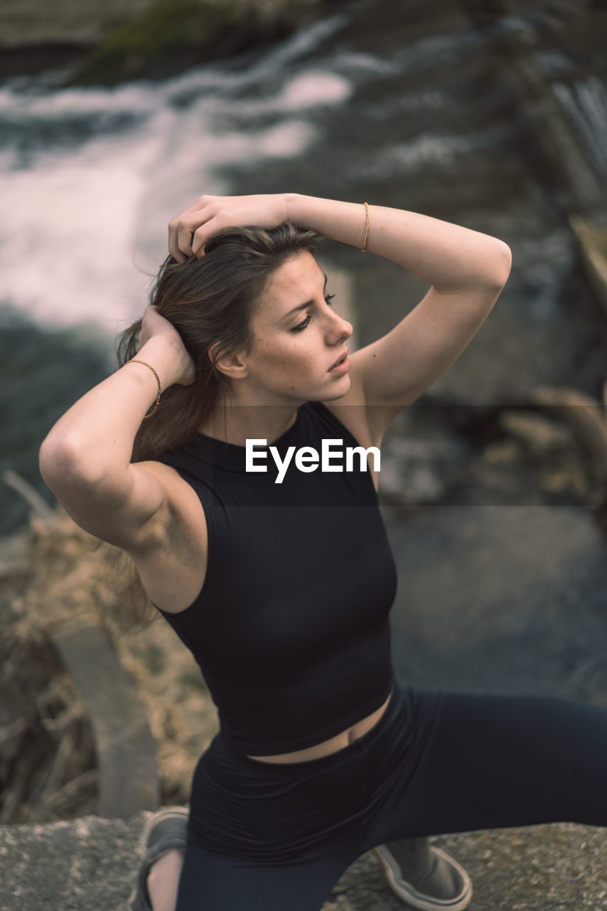 MIDSECTION OF WOMAN LOOKING AWAY WHILE STANDING OUTDOORS