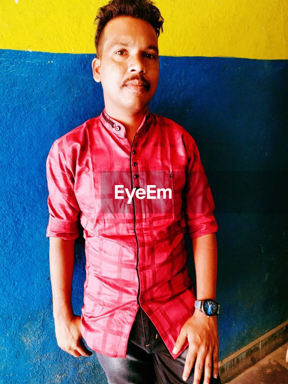 FULL LENGTH PORTRAIT OF YOUNG MAN STANDING AGAINST WALL