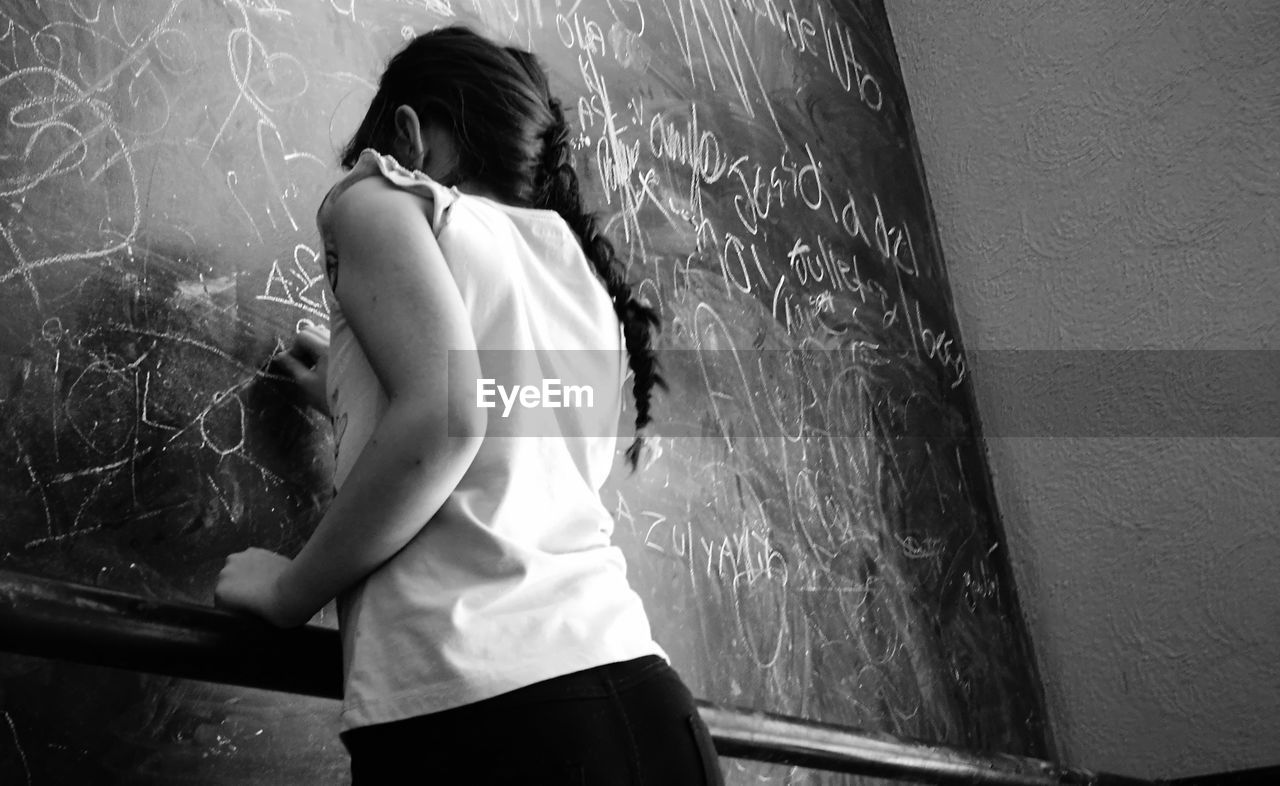 Rear view of girl drawing on blackboard