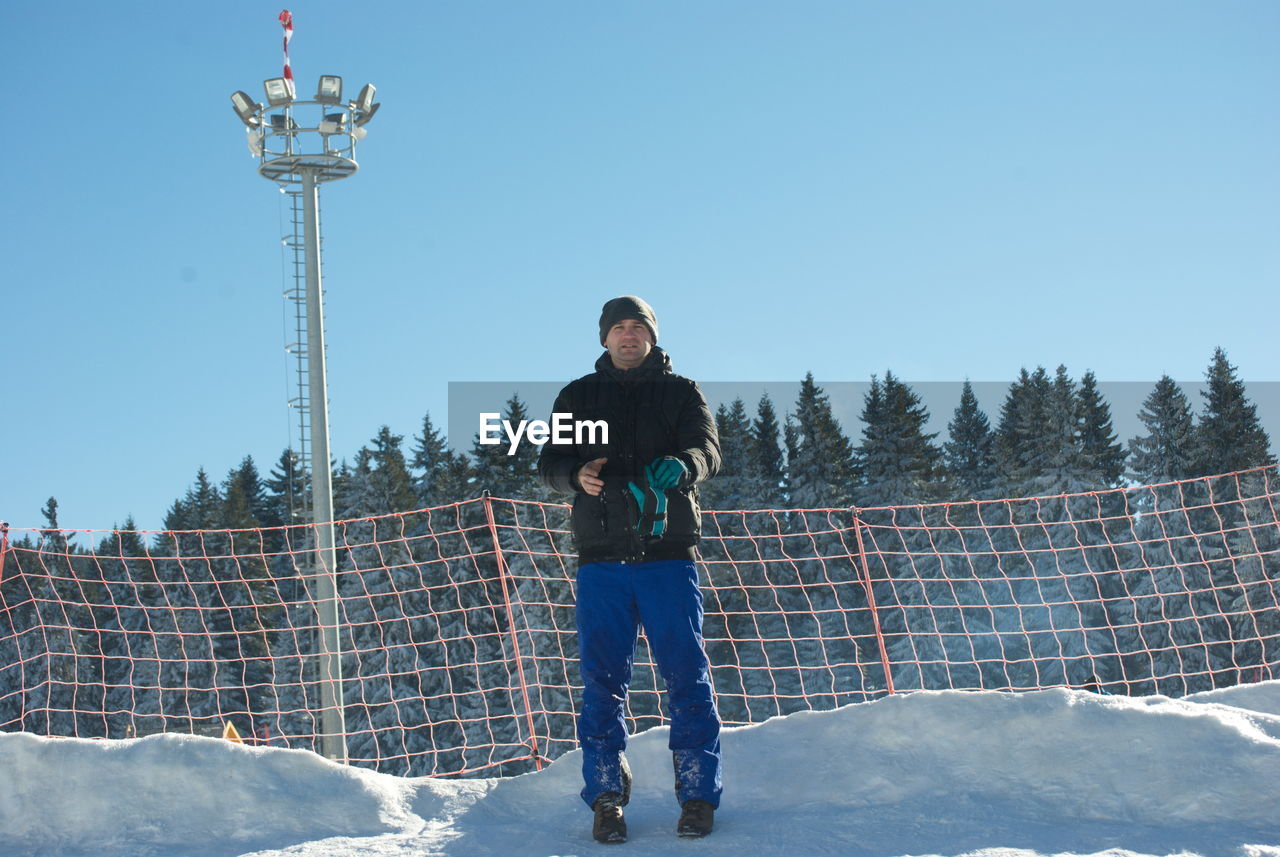 MAN STANDING ON SNOW AGAINST CLEAR BLUE SKY