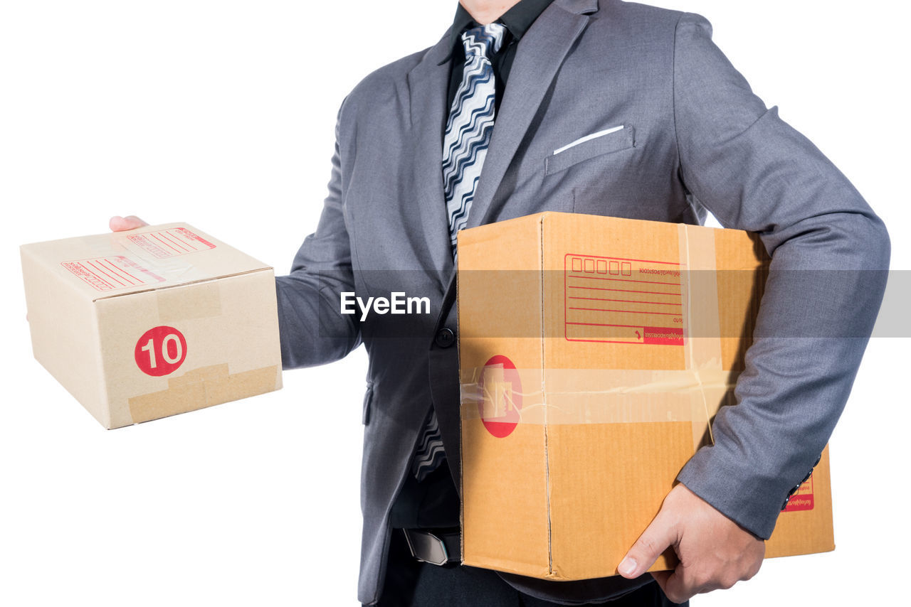 MIDSECTION OF MAN WITH UMBRELLA STANDING IN FRONT OF BOX