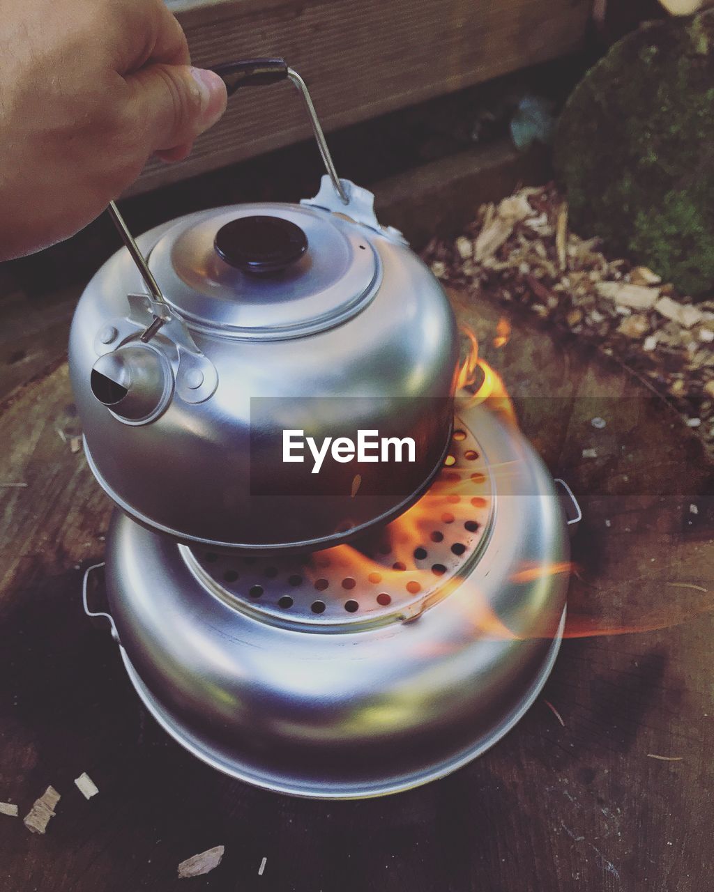 Close-up of hand holding tea kettle on stove