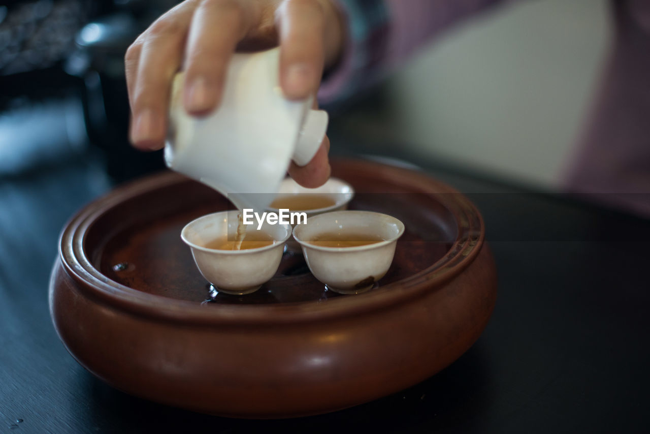 Cropped image of hand pouring chinese tea in cup