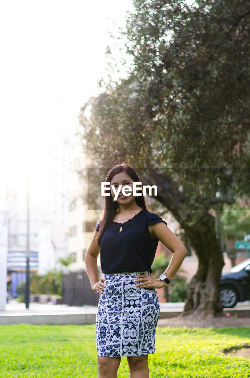 PORTRAIT OF A SMILING YOUNG WOMAN AGAINST PLANTS