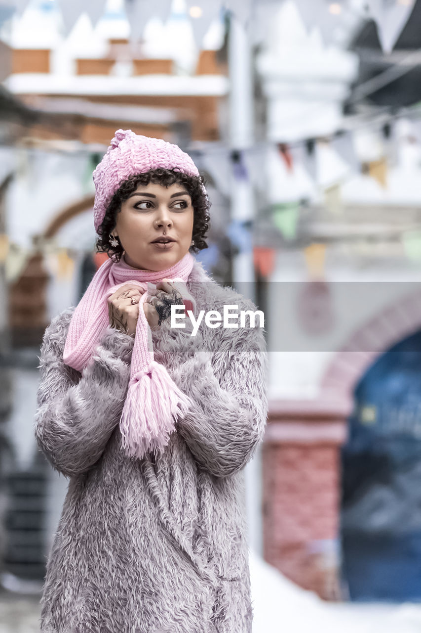 A stylish woman in pastel-colored warm clothes outdoors in the city in winter.snowfall,cold weather.