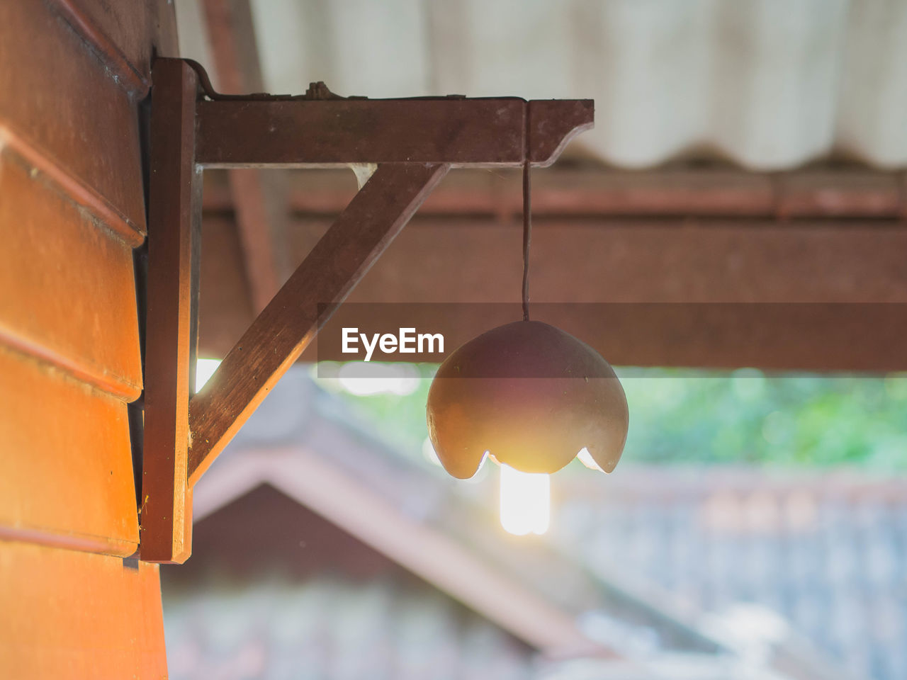 CLOSE-UP OF LIGHT BULB HANGING AGAINST METAL STRUCTURE