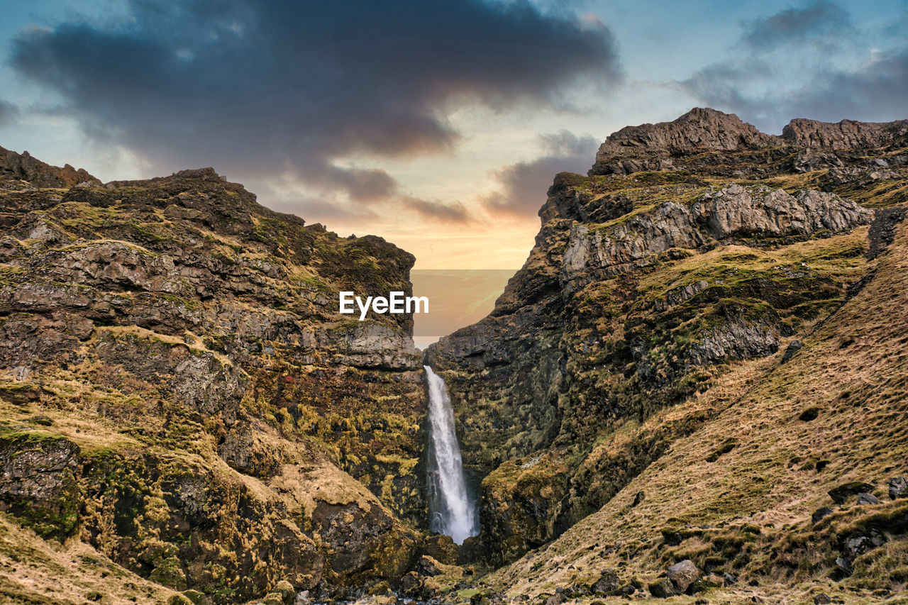 SCENIC VIEW OF WATERFALL AGAINST ROCKS