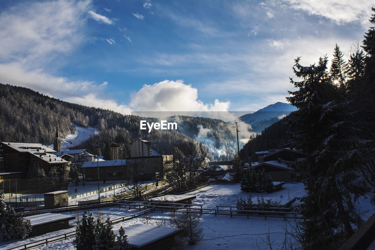 Houses amidst mountains against sky during winter