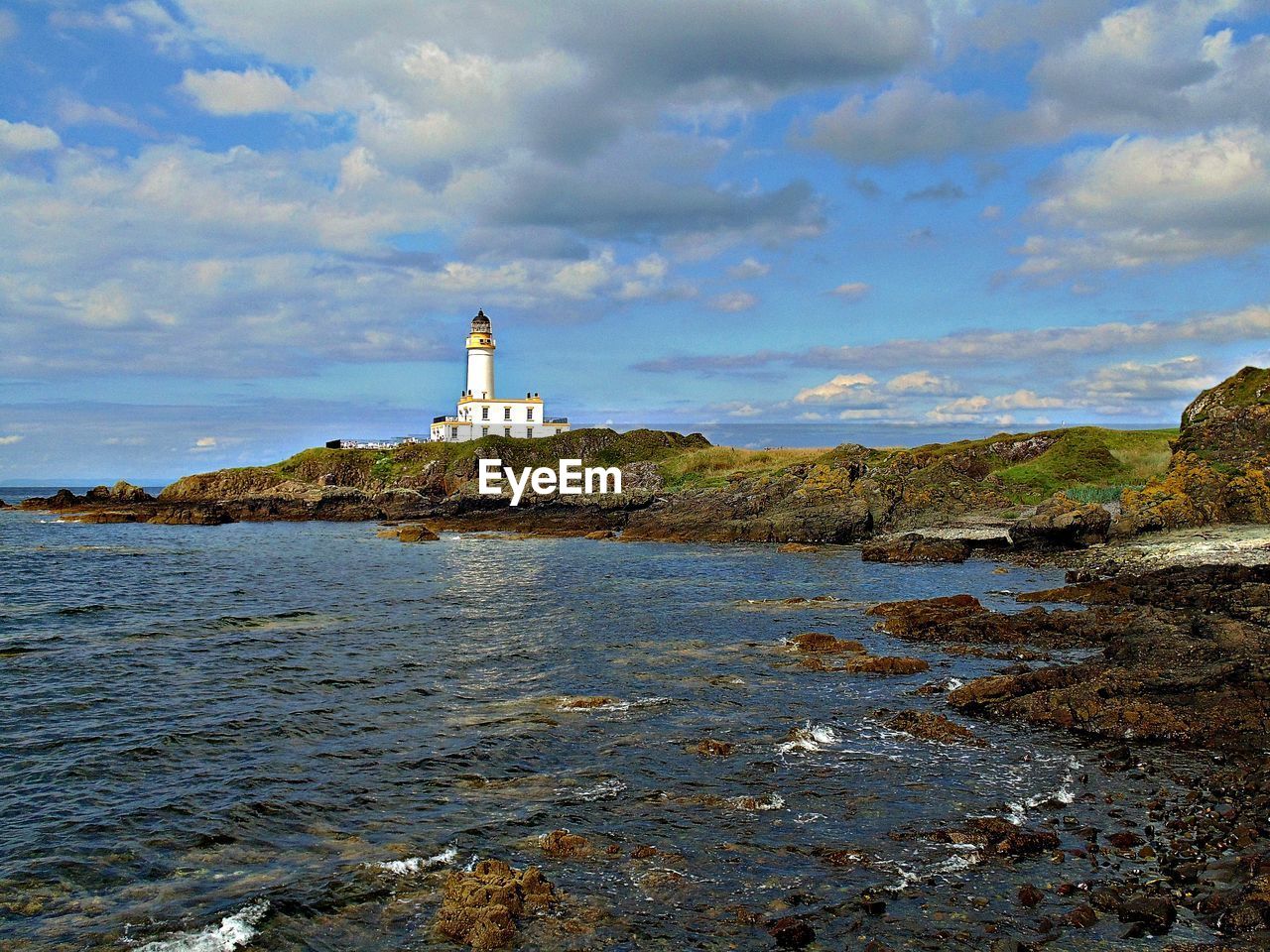 Lighthouse amidst sea and buildings against the sky