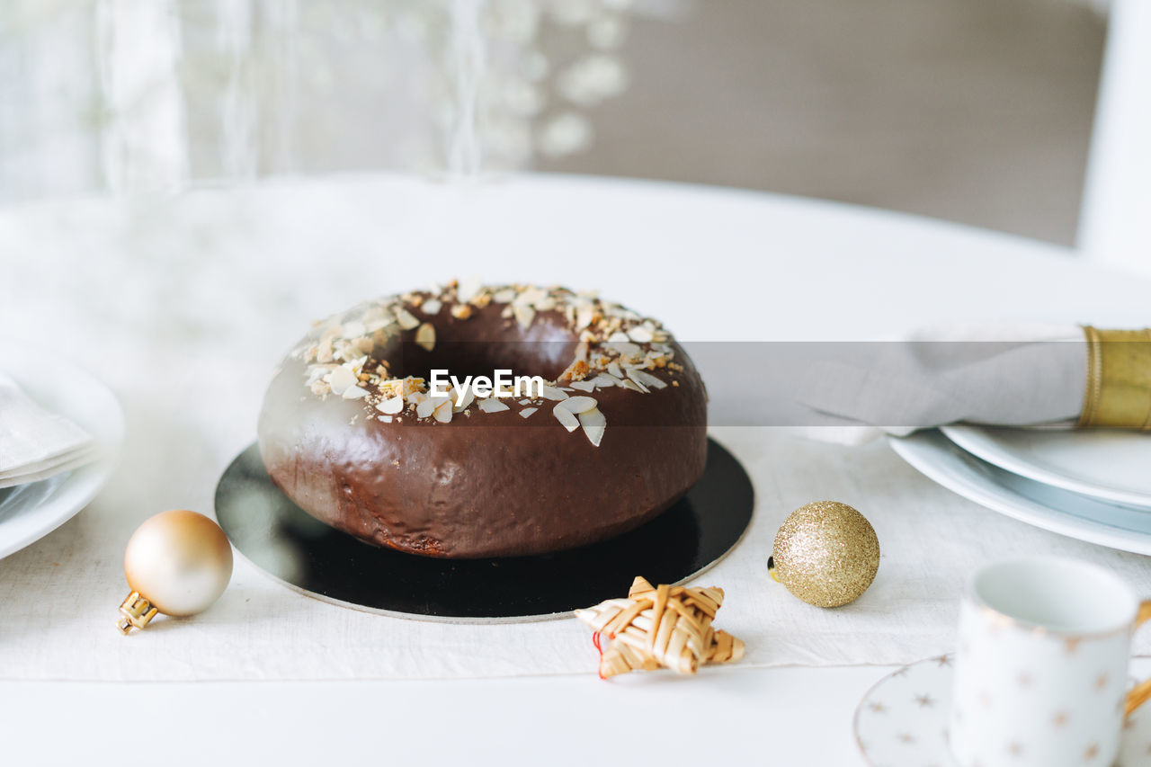 Large round chocolate almond cake on table with new year serving, christmas white scandinavian 