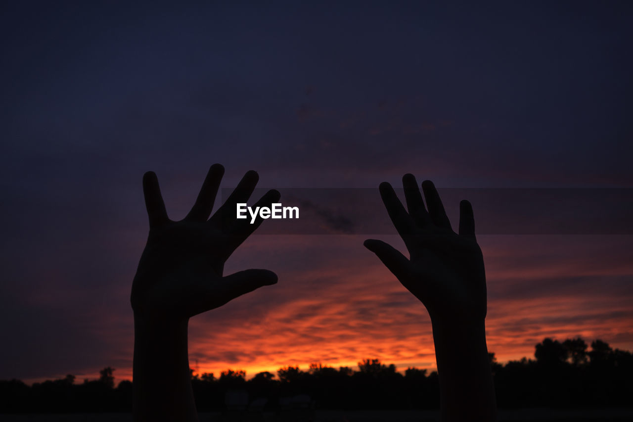 SILHOUETTE OF HAND AGAINST SKY DURING SUNSET