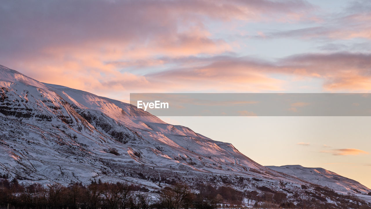 Early morning glow on the winter hills as sunrises on the campsie fells behind lennoxtown, scotland