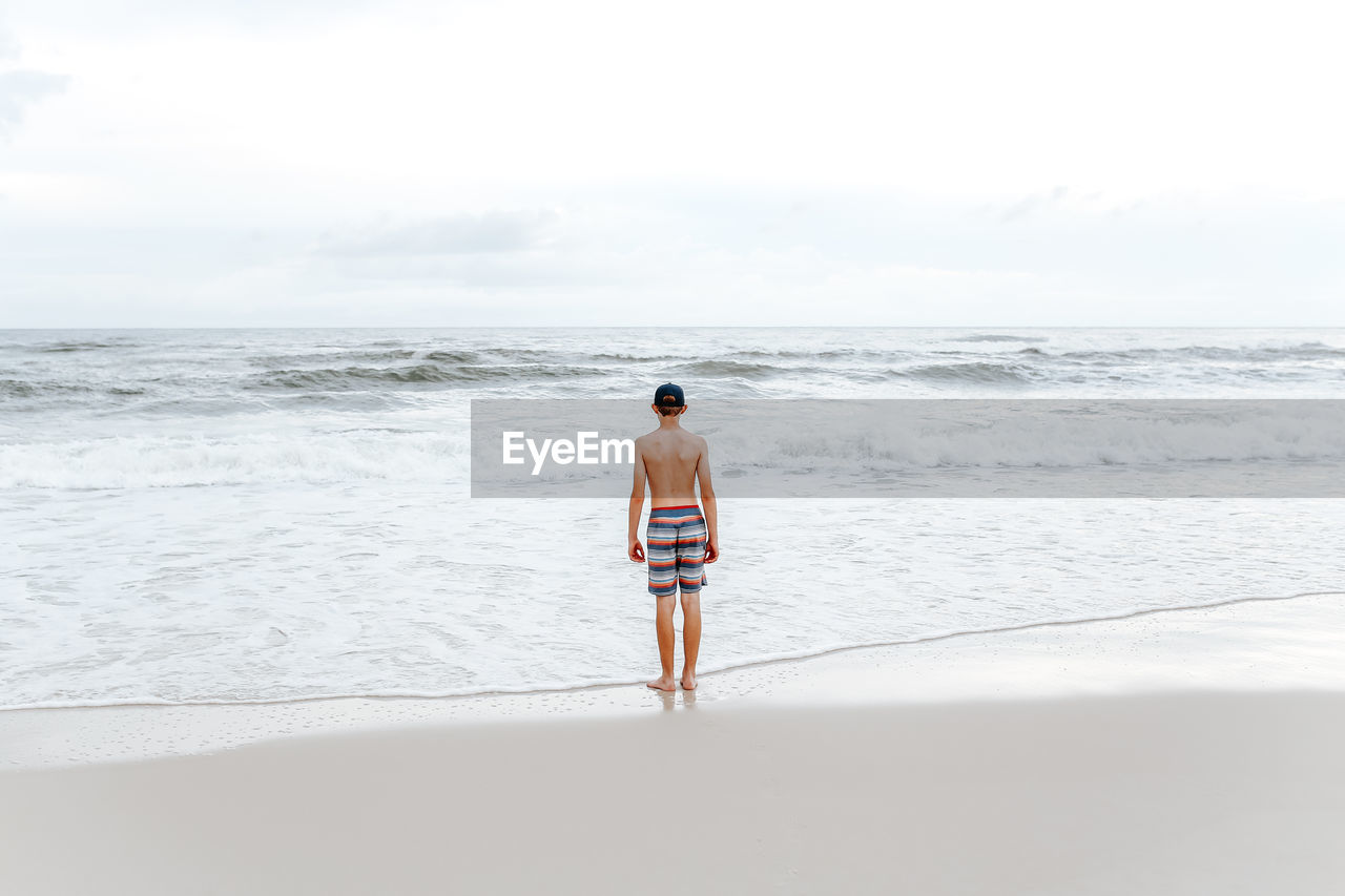 Full length rear view of teenage boy on beach