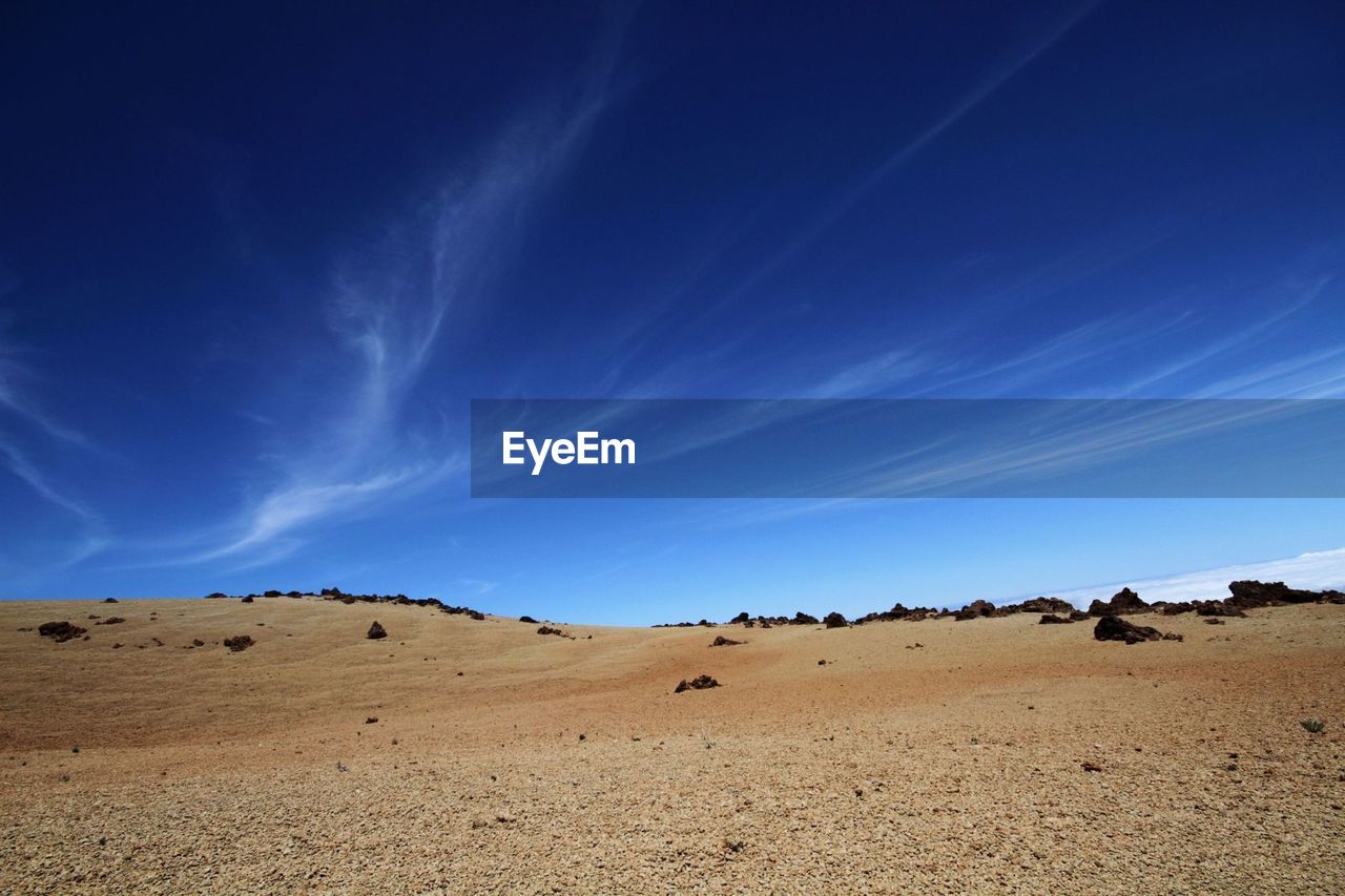 Scenic view of desert against cloudy sky