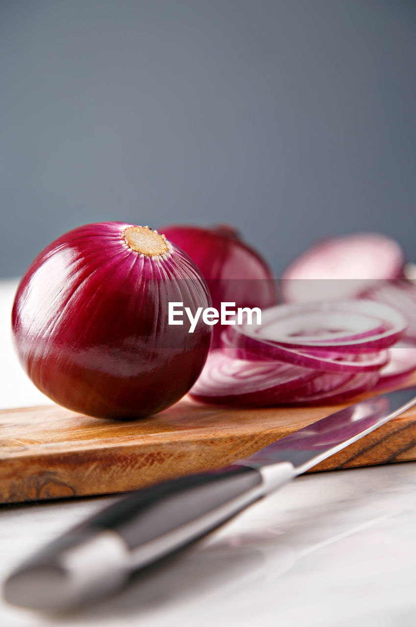 Close-up of onions on cutting board with knife on table