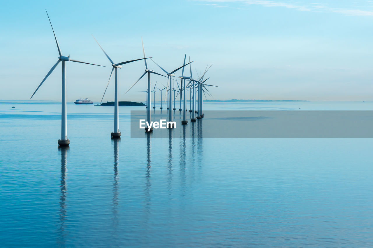 Windmills on sea against sky 