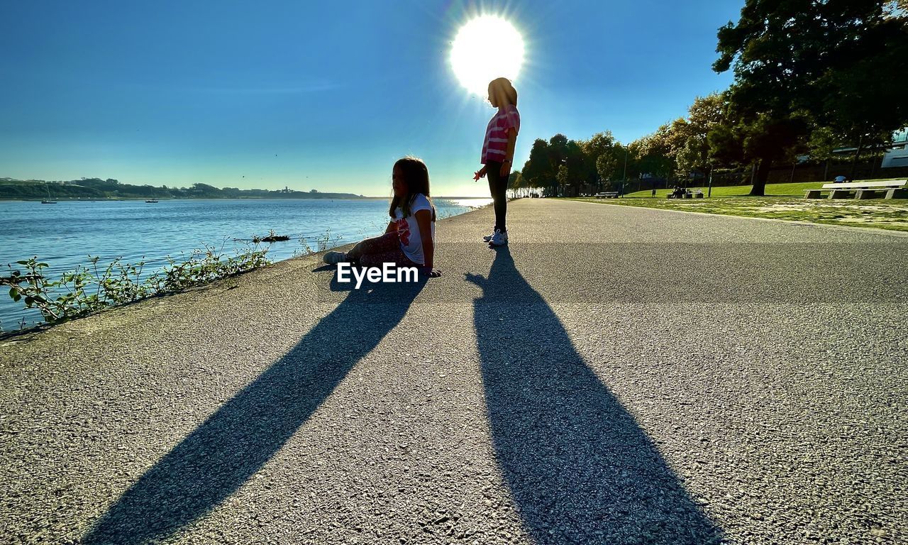 sunlight, shadow, sky, nature, two people, child, childhood, family, women, togetherness, adult, female, parent, full length, one parent, water, sunny, bonding, leisure activity, horizon, men, lifestyles, day, back lit, lens flare, beach, emotion, father, positive emotion, land, summer, love, outdoors, plant, sea, rear view, morning, tree, beauty in nature, walking, casual clothing