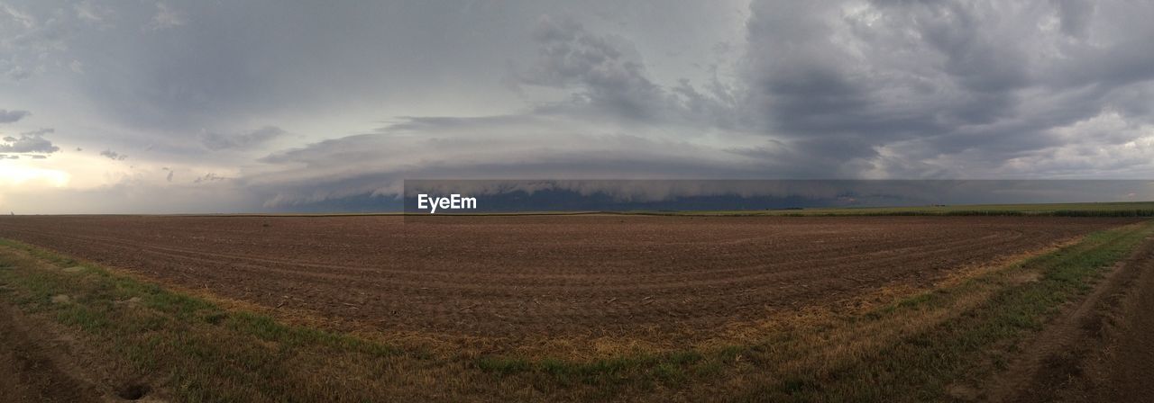 Panoramic view of field against cloudy sky