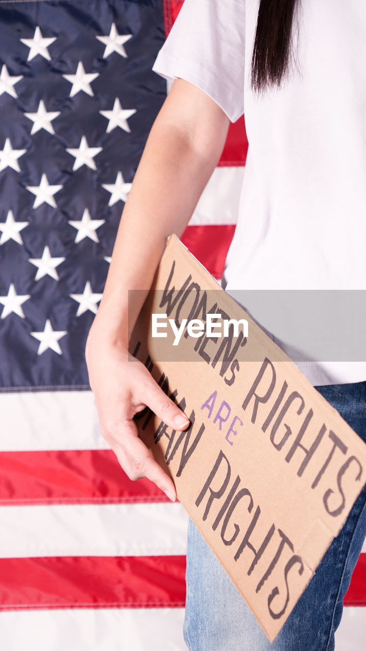 midsection of woman holding text on flag