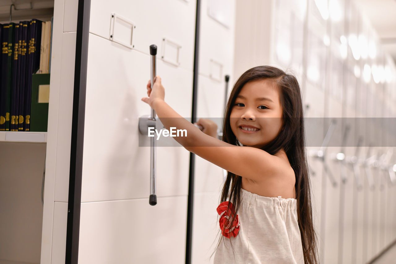 Portrait of smiling girl opening locker