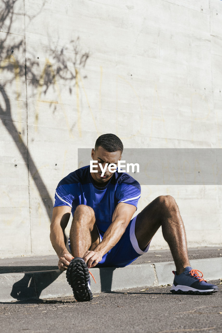 Full length of african american athlete tying shoelaces